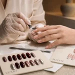 Idee ongle semi permanent : technicienne pose base gel semi-permanente sur ongles