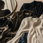 Test style vestimentaire : cinq pièces mode noir, crème et beige sur table en bois